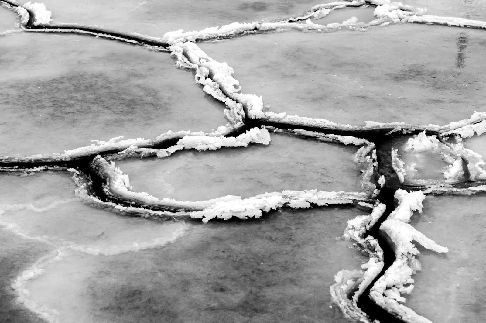 Close-up view of a cracked ice surface with jagged lines and frost formations along the edges