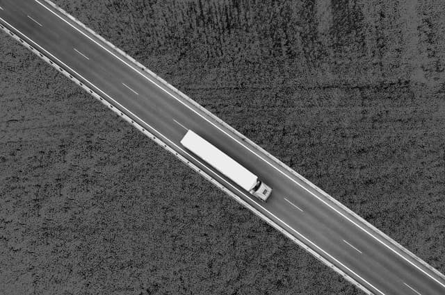 Aerial overhead view of a semi truck driving between canola fields used for biodiesel