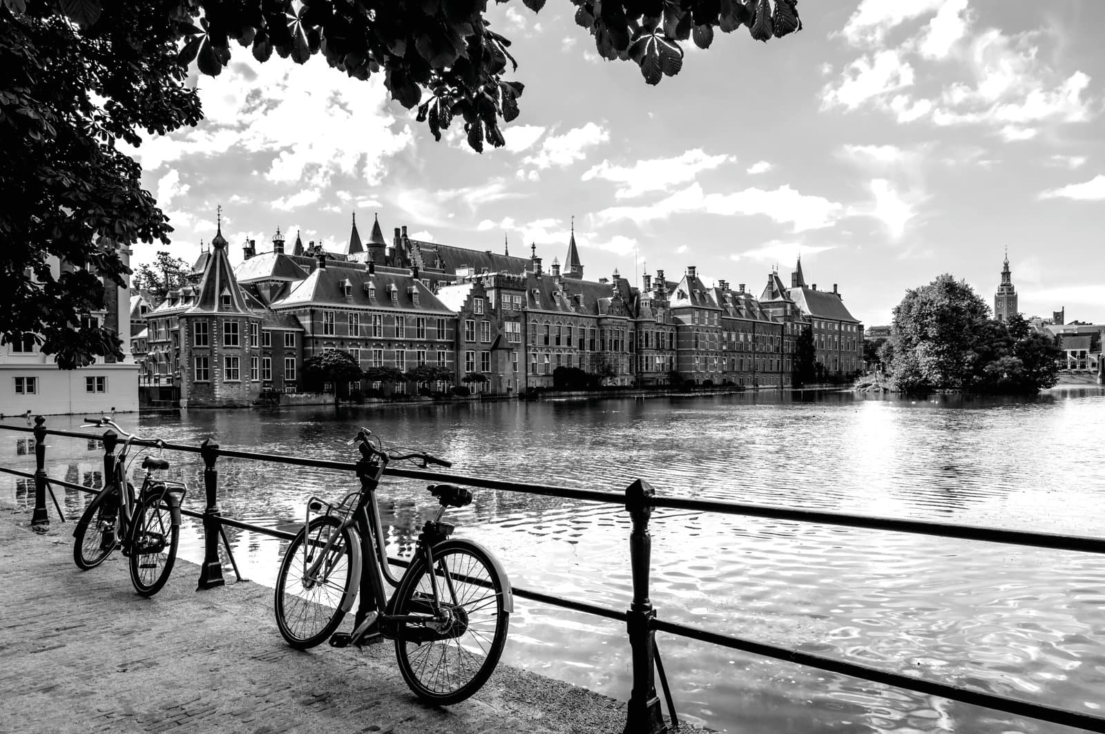 View of historic canal‑side buildings with two bicycles parked along a railing by the water.