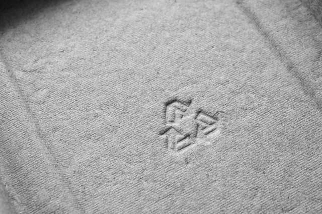 Embossed recycling symbol stamped into a piece of cardboard