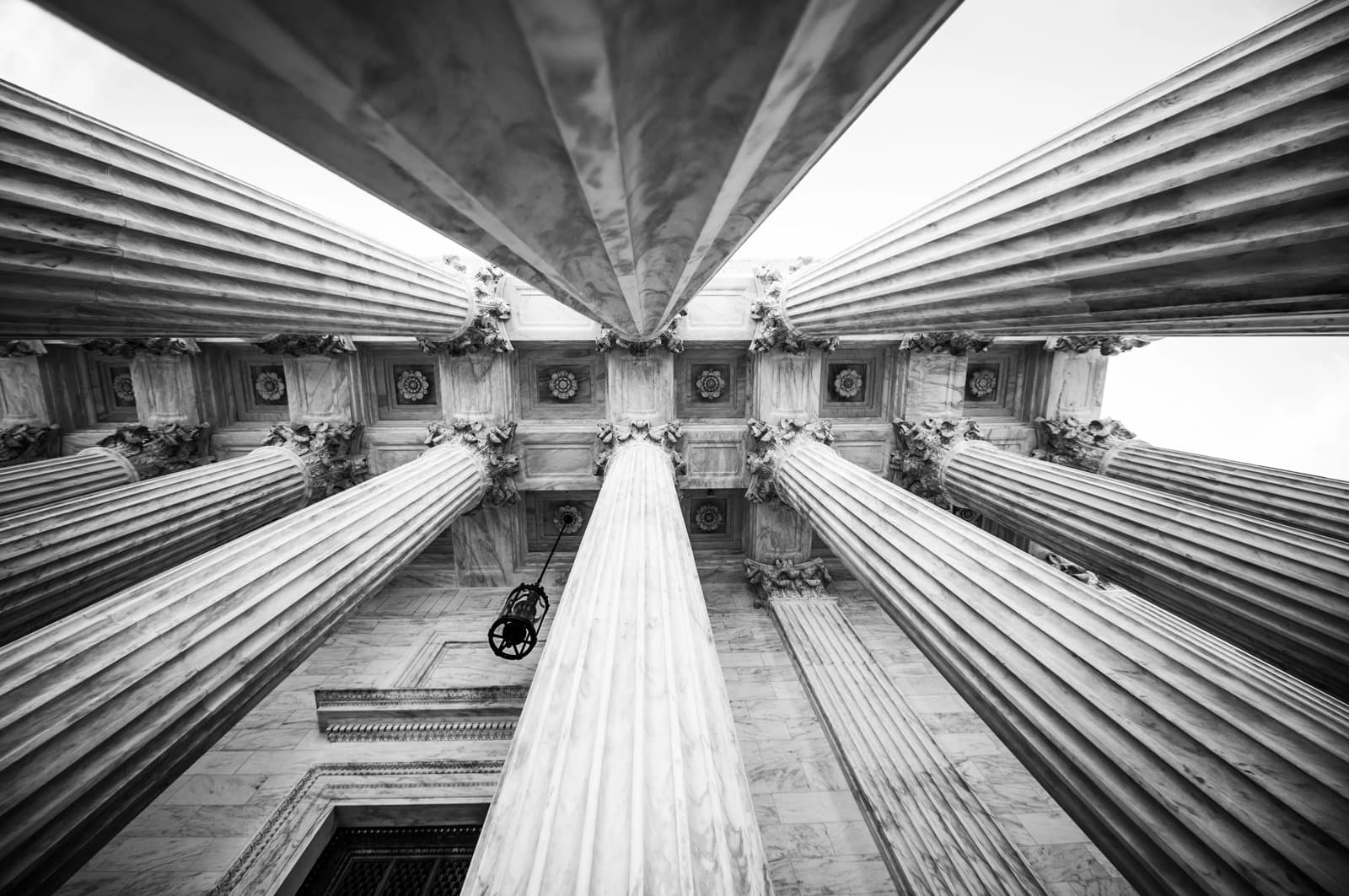 upward view of classical stone columns supporting a courthouse building.