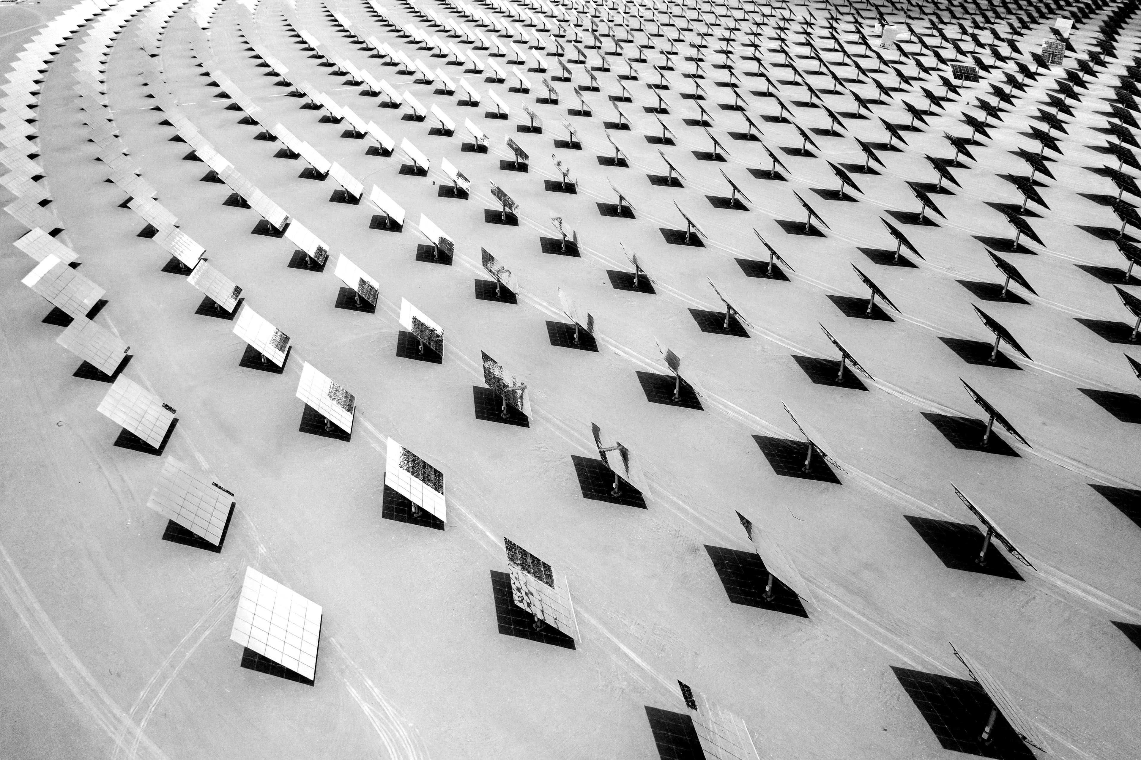 Black and white aerial shot of a circular array of solar panels shining in the sun