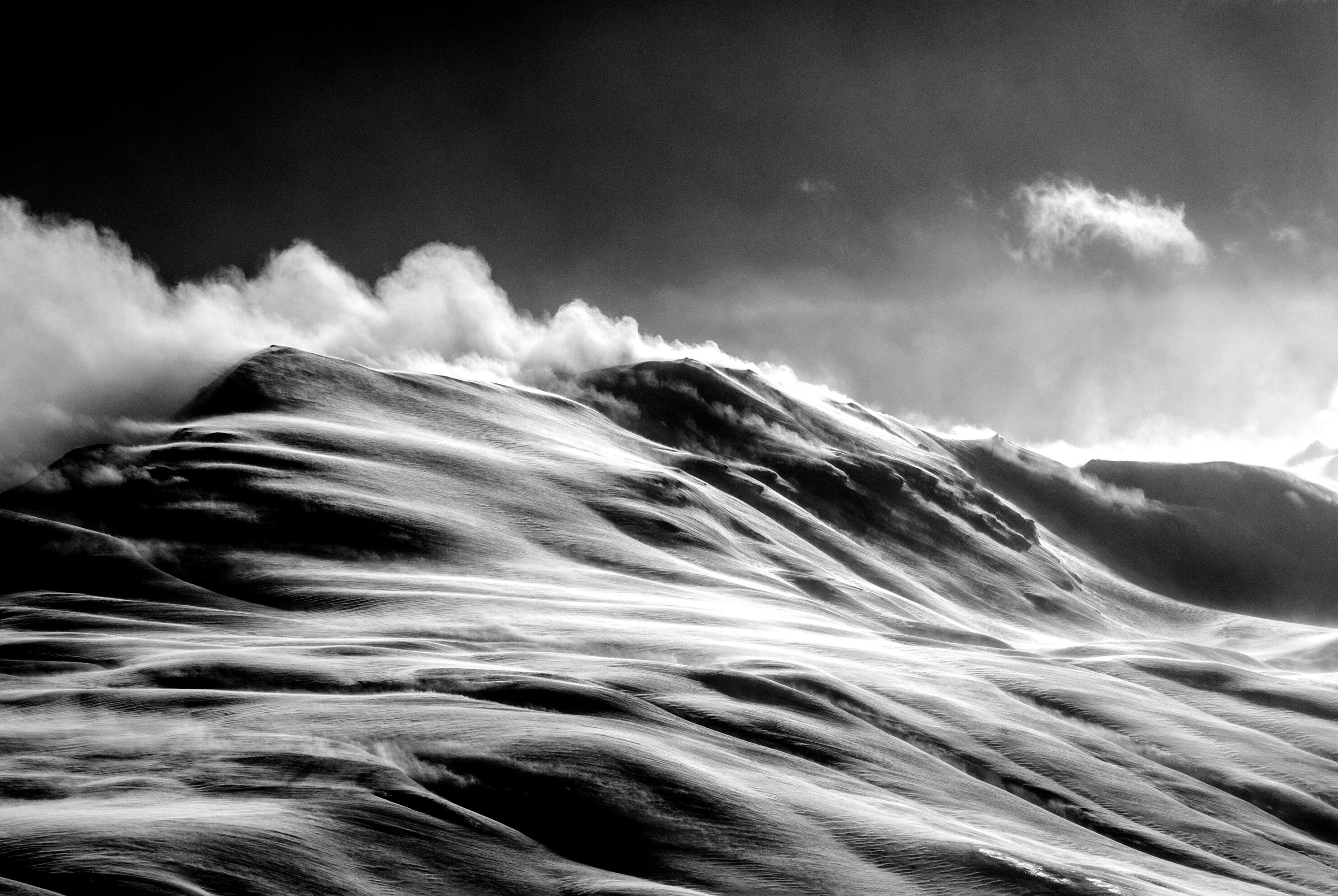 Black and white image of a stormy sea with spray against a grey sky and clouds