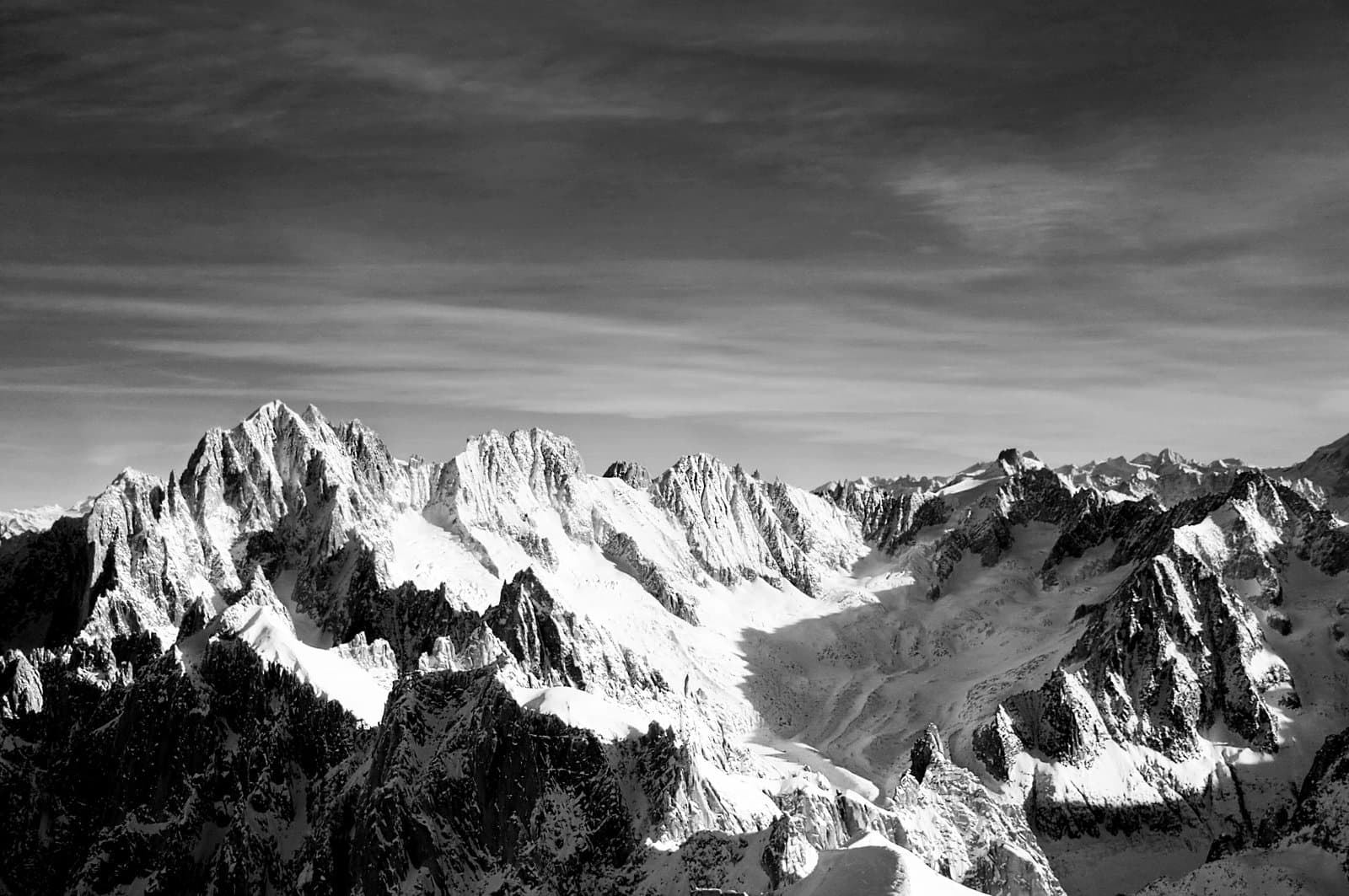 A rugged, snow-covered mountain range under a cloudy sky.