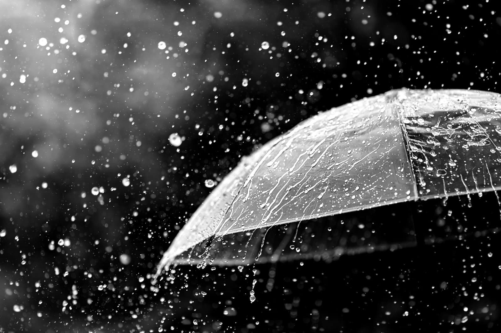 Transparent umbrella under heavy rain against water drops splash