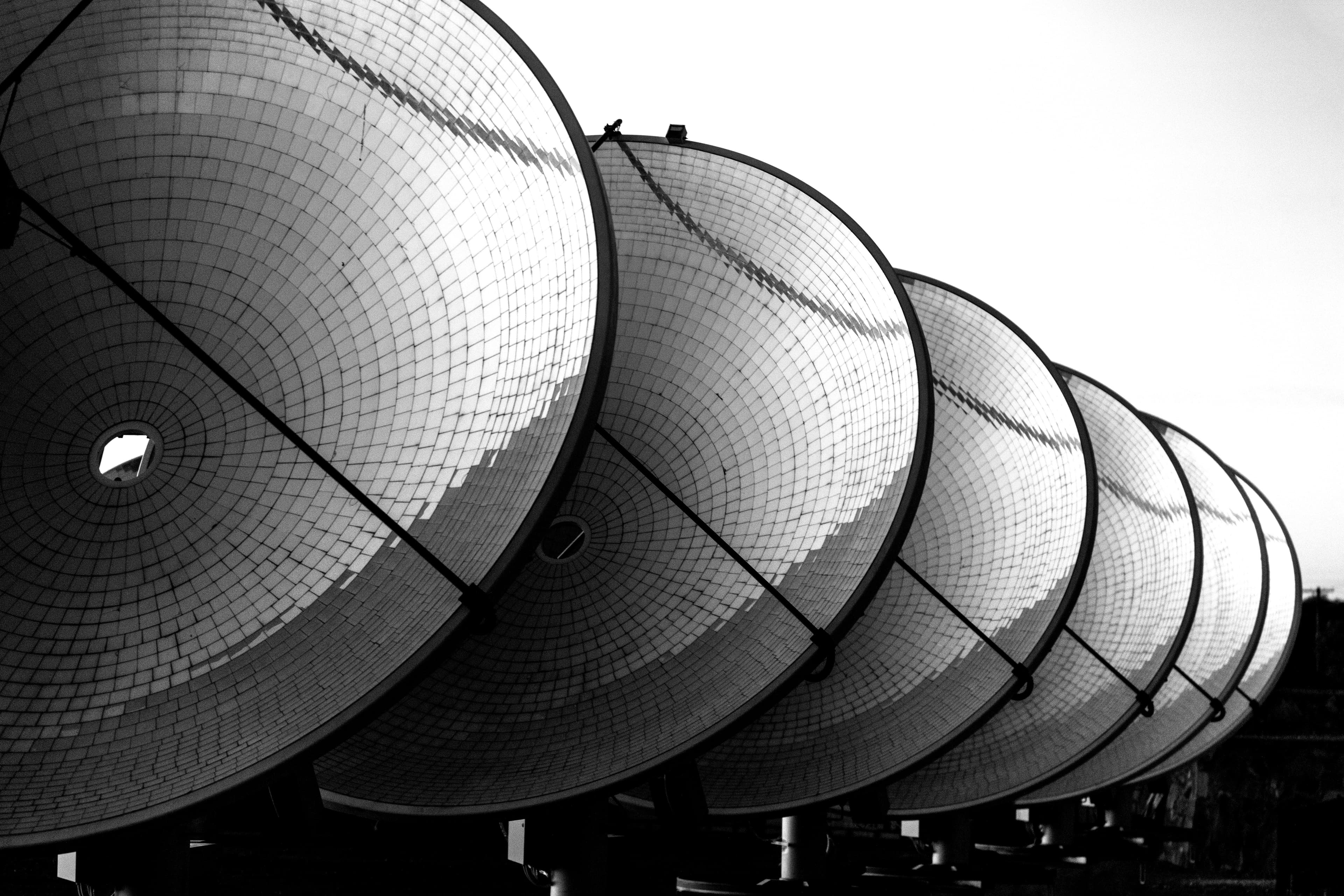 A line of six large solar dishes face towards the sun at thermal power station