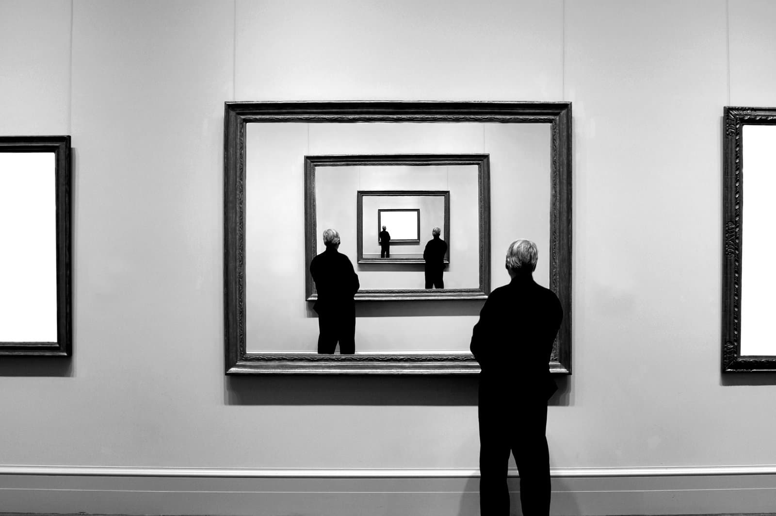 Man looking into many mirrors