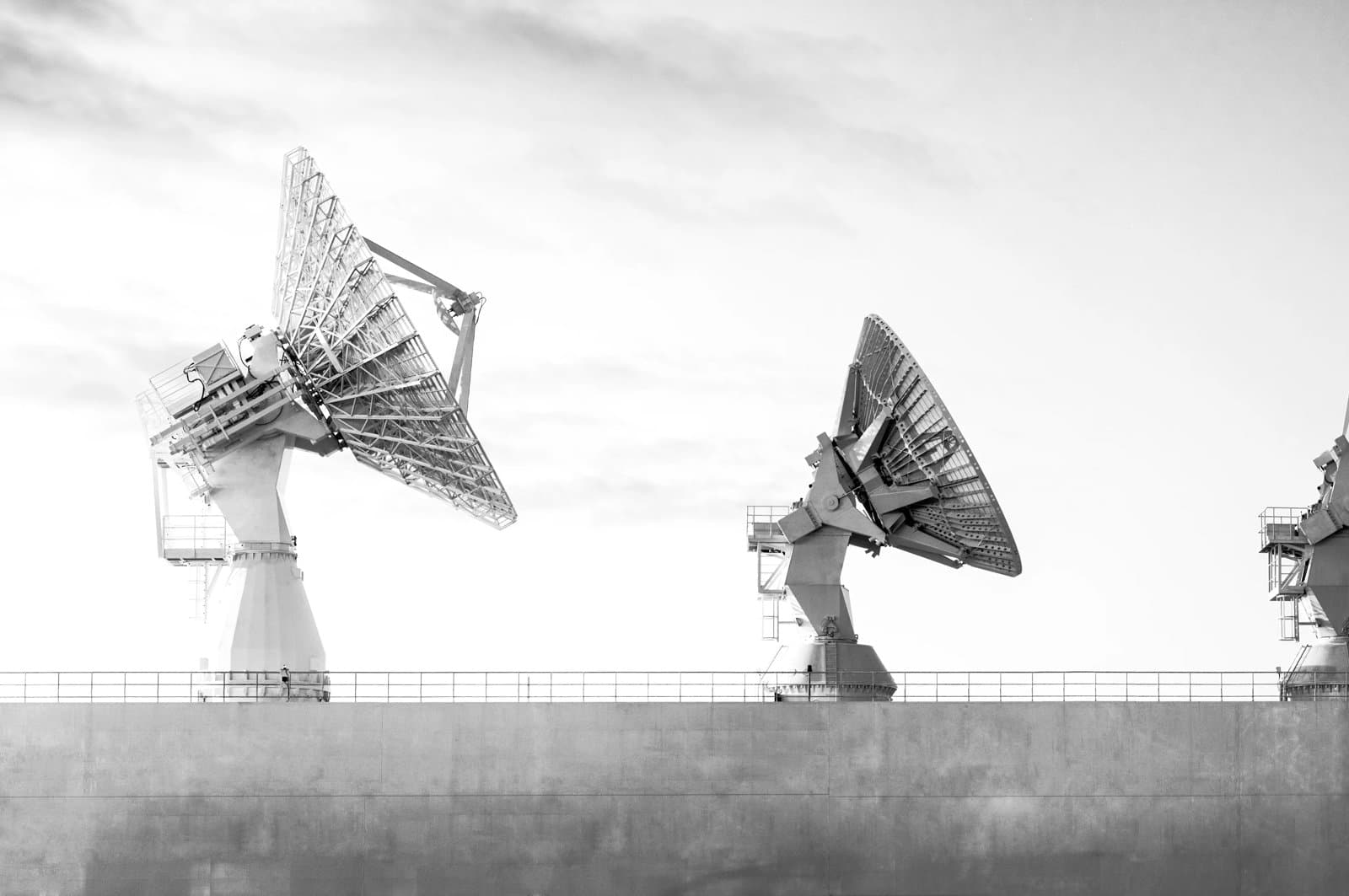 Three satellite dishes perched high atop the deck of a vessel used in tracking rocket trajectories.