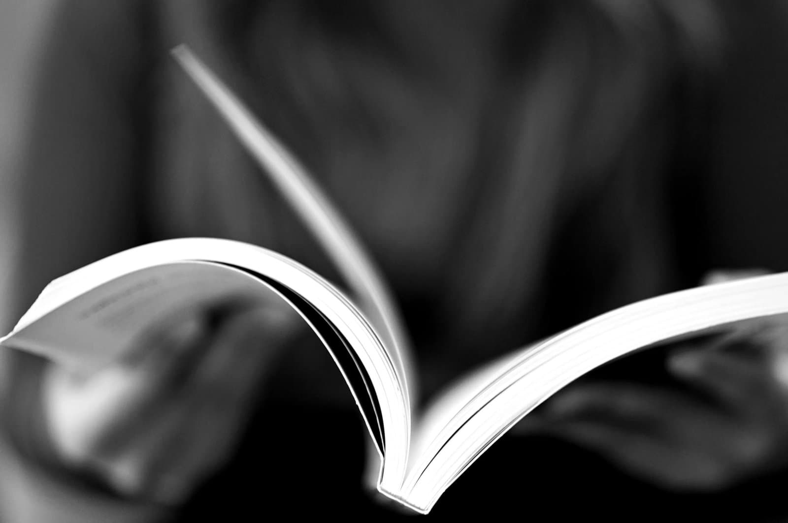 Close-up hand of a person reading an open book.